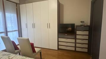 Une chambre à coucher avec un lit, une armoire, un bureau et un téléviseur.