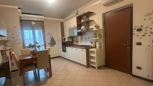 Een moderne keuken met witte kastjes, een eettafel met stoelen en een grote deur met vlinderstickers.
