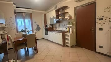 Una cocina moderna con armarios blancos, una mesa de comedor con sillas y un gran ventanal con un dibujo de mariposa.