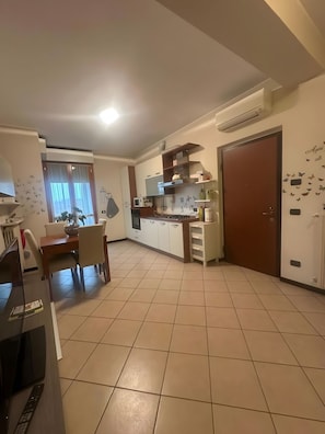Cuina moderna amb armaris blancs, taula de dinar amb caires i una porta gran amb un adhesiu de papallona.