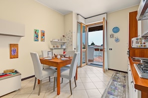 A modern kitchen with a dining area, a view through the open door, and various kitchen appliances.