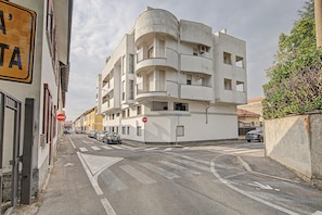 A multi-story building with balconies, a no entry sign, and parked cars on a street.