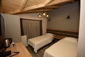 Een hotelkamer met twee bedden, een houten plafond, een klein tafeltje met een waterkoker en telefoon, en een gordijn.