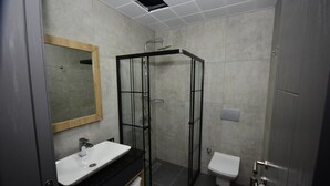 A modern bathroom with a glass shower enclosure, a white sink, and a toilet. - Koru Otel & Restaurant (Artvin)