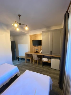 Een hotelkamer met twee bedden, een bureau met stoel, een televisie en een kledingkast.