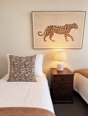 Une chambre d’hôtel avec un lit, une table de chevet avec une lampe et une œuvre d’art représentant un guépard, encadrée, accrochée au mur.