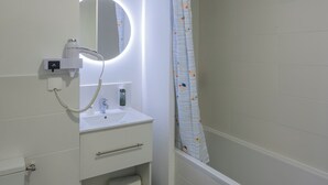 Un baño con inodoro, lavamanos, espejo y bañera.