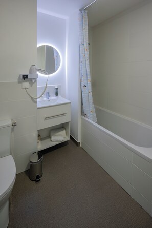 A bathroom with a toilet, sink, mirror, and bathtub. - All Suites Appart Hotel Le Havre (Le Havre)
