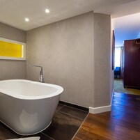 A modern bathroom with a freestanding bathtub, a visible shower area, and a wooden floor.