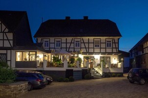 A traditional half-timbered building with a well-lit entrance and a visible staircase leading to the main entrance.