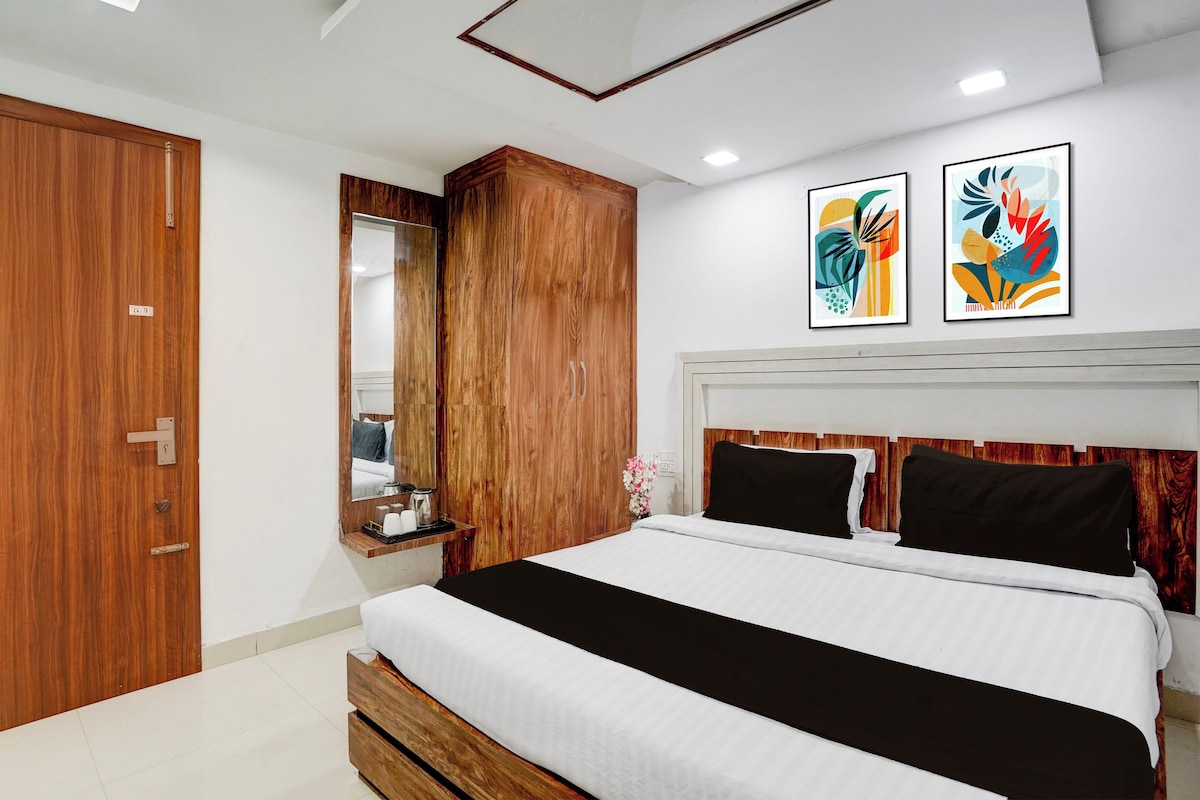 A modern bedroom with a large bed, wooden wardrobe, and two wall-mounted artworks.