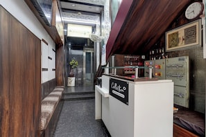 A narrow hallway with a reception desk, a clock, and a wall-mounted fan.