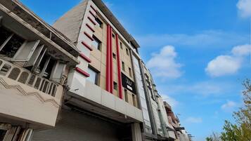 A multi-story building with a modern architectural design, featuring a prominent vertical red stripe and a sign indicating a business or commercial use.