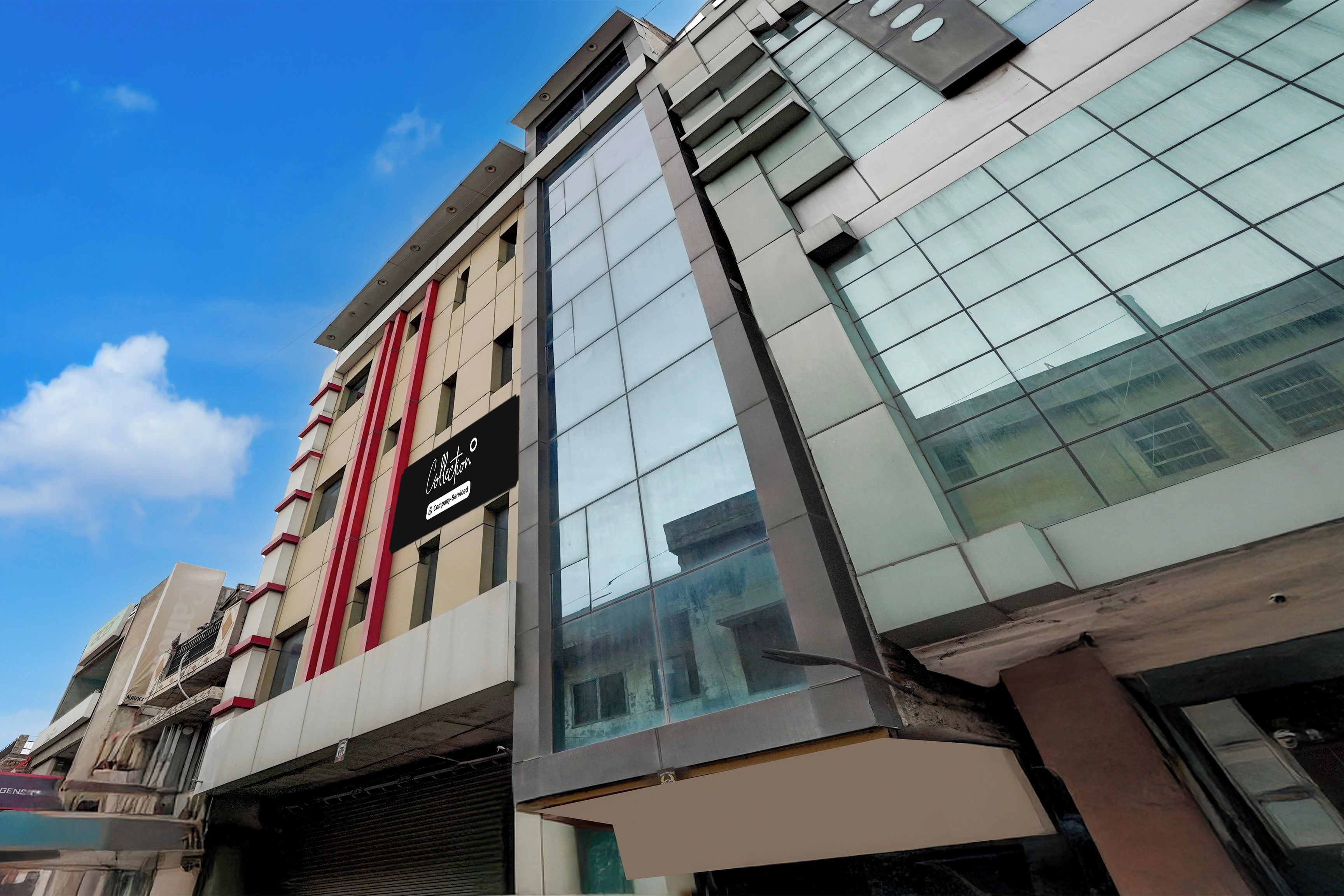 Un edificio de varios pisos con un estilo arquitectónico moderno, destacando un amplio frente de vidrio y un letrero que indica un servicio de empresa.