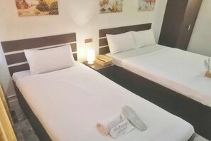 Habitació d'hotel amb dos llits individuals, una tauleta de nit amb una làmpada i una obra d'art penjada a la paret.