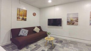 A living room with a brown sofa, a round wooden coffee table, and two wall-mounted paintings. - VG Pension and Residences by Zuzu (Cebu City)