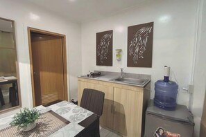 A compact kitchen with a sink, a water dispenser, and a refrigerator. - VG Pension and Residences by Zuzu (Cebu City)