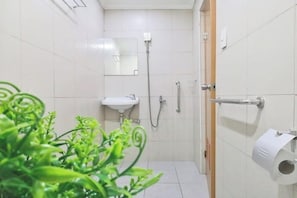 A bathroom with a sink, mirror, shower, and toilet paper. - VG Pension and Residences by Zuzu (Cebu City)