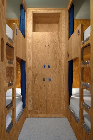 Quarto com beliches de madeira, números 3 a 6 nas portas.