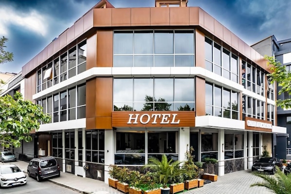 A modern hotel with a prominent 'HOTEL' sign, large windows, and a landscaped entrance area. - Garden Room Suit Hotel (Istanbul)