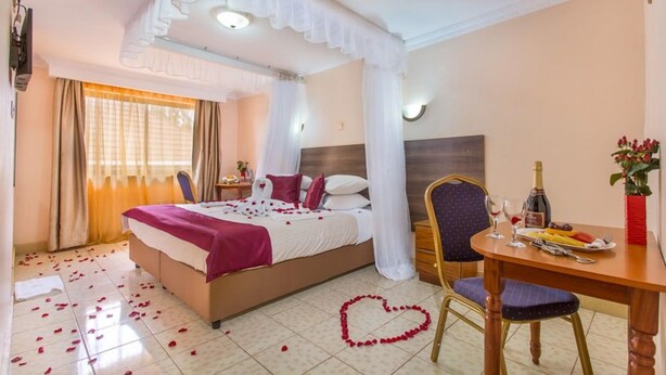 A hotel room with a bed, a dining table, and a heart-shaped decoration on the floor. - Phoenicia Hotel (Kiambu)