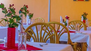 A restaurant with round tables, chairs, and potted plants. - Phoenicia Hotel (Kiambu)