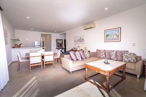 Un'area living moderna con un tavolo da pranzo, divani e una cucina sullo sfondo.