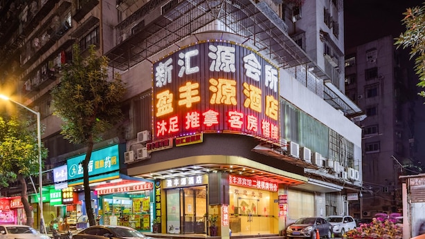 A multi-story building with illuminated signage, a storefront, and parked cars. - Ying Feng Yuan Hotel (Guangzhou)