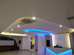 A modern hotel lobby with a reception desk, seating area, and a ceiling with recessed lighting and blue accent lighting. - Ying Feng Yuan Hotel (Guangzhou)