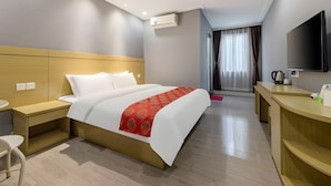 A hotel room with a bed, bedside table, a desk with a chair, a TV, and an air conditioning unit. - Ying Feng Yuan Hotel (Guangzhou)