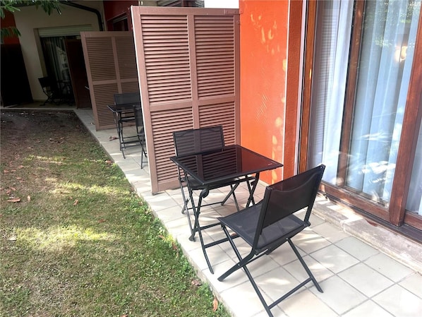 An outdoor patio area with a table and chairs, a sliding door, and a view of a building through a window. - Sure Hotel by Best Western Saint-quentin Ouest (Holnon)