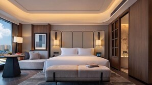 A modern hotel room with a large bed, bedside lamps, a sofa, a desk, and a view of the city. - Wyndham Changsha Yanghu (Changsha)