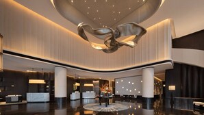A modern lobby with a central reception desk, a unique sculptural light fixture, and a polished floor. - Wyndham Changsha Yanghu (Changsha)