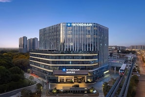 A modern Wyndham hotel with a prominent glass facade, a rooftop terrace, and a connected pedestrian bridge. - Wyndham Changsha Yanghu (Changsha)