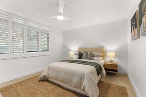 A bedroom with a bed, bedside tables, a ceiling fan, and a window with blinds. - New Farm Hideaway with Courtyard - 2Bed-1Bath-1Car (New Farm)