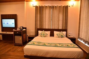 A hotel room with a bed, a desk with a computer, a television, and curtains. - Mastiff Hotel Palampur (Palampur)