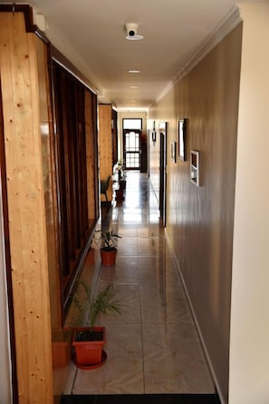 Un pasillo con paneles de madera, plantas en macetas y piso de baldosas.
