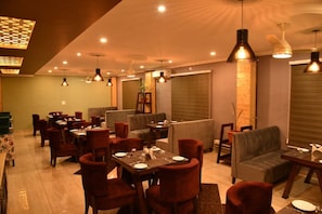Un restaurante con varias mesas y sillas, ventiladores de techo e iluminación colgante.