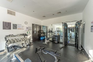 A gym with various exercise equipment, including dumbbells, exercise balls, and a squat rack. - Sunny Marina Retreat - 1BR Near Metro station (Dubai)