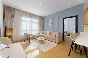 A modern living room with a sofa, chairs, a coffee table, and a dining area with a table and chairs. - Sunny Marina Retreat - 1BR Near Metro station (Dubai)