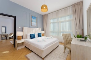 A hotel room with a large bed, bedside tables, a desk with a laptop, and a view of the outdoors. - Sunny Marina Retreat - 1BR Near Metro station (Dubai)