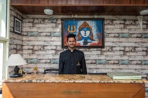A reception desk with a wooden finish and a framed painting above it. - Shining Hills by Hotel Tranquility (Mussoorie)