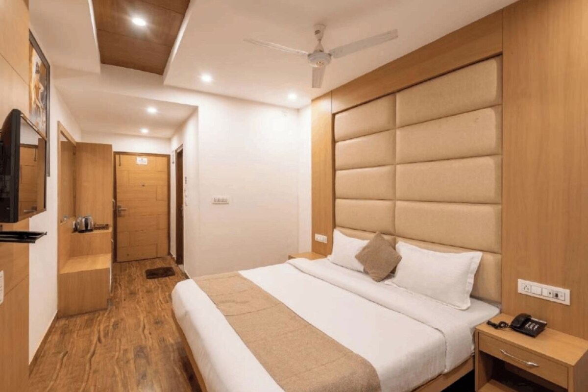 Une chambre d’hôtel avec un lit, une table de chevet et un téléviseur fixé au mur.
