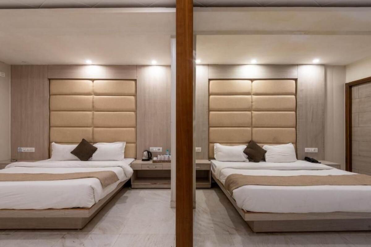 Una habitació d'hotel amb dos llits, un panell frontal de fusta, taules de nit i un mirall.