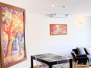 Una habitación con una mesa de comedor, sillas, un sofá y dos cuadros en la pared.
