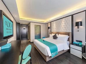 Ett hotellrum med en säng, sängbord, ett skrivbord och en stol.