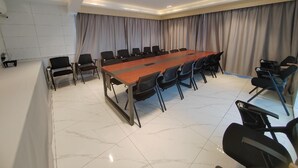 Een vergaderruimte met een lange tafel, stoelen en gordijnen.