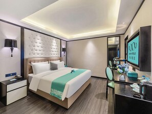 A modern hotel room with a large bed, bedside tables, a desk with a chair, a flat-screen TV, and a decorative mirror. - Xana Hotelle (Guangzhou)