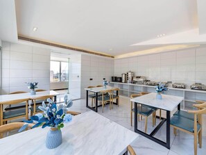 A modern kitchen with white tiles, wooden furniture, and a view through a glass door. - Xana Hotelle (Guangzhou)