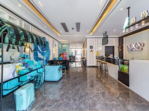 A hotel lobby with a reception desk, seating area, and a large window with decorative items. - Xana Hotelle (Guangzhou)